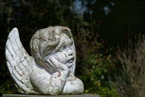 putto child angel statue of ceramic with flaking white paint